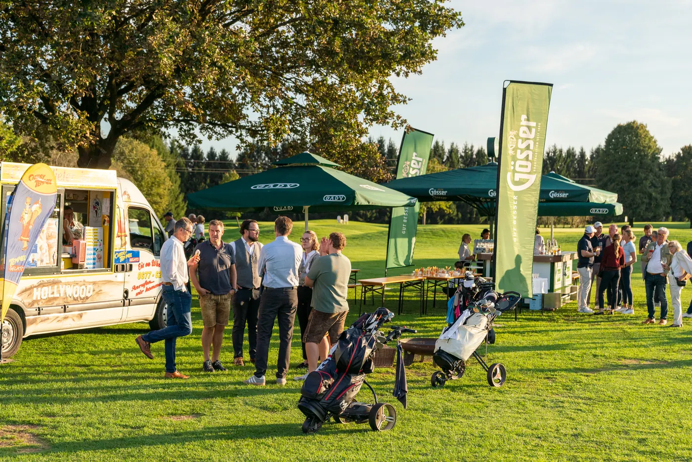 Gäste und Flights versammeln sich in der Abendsonne vor dem Clubhaus